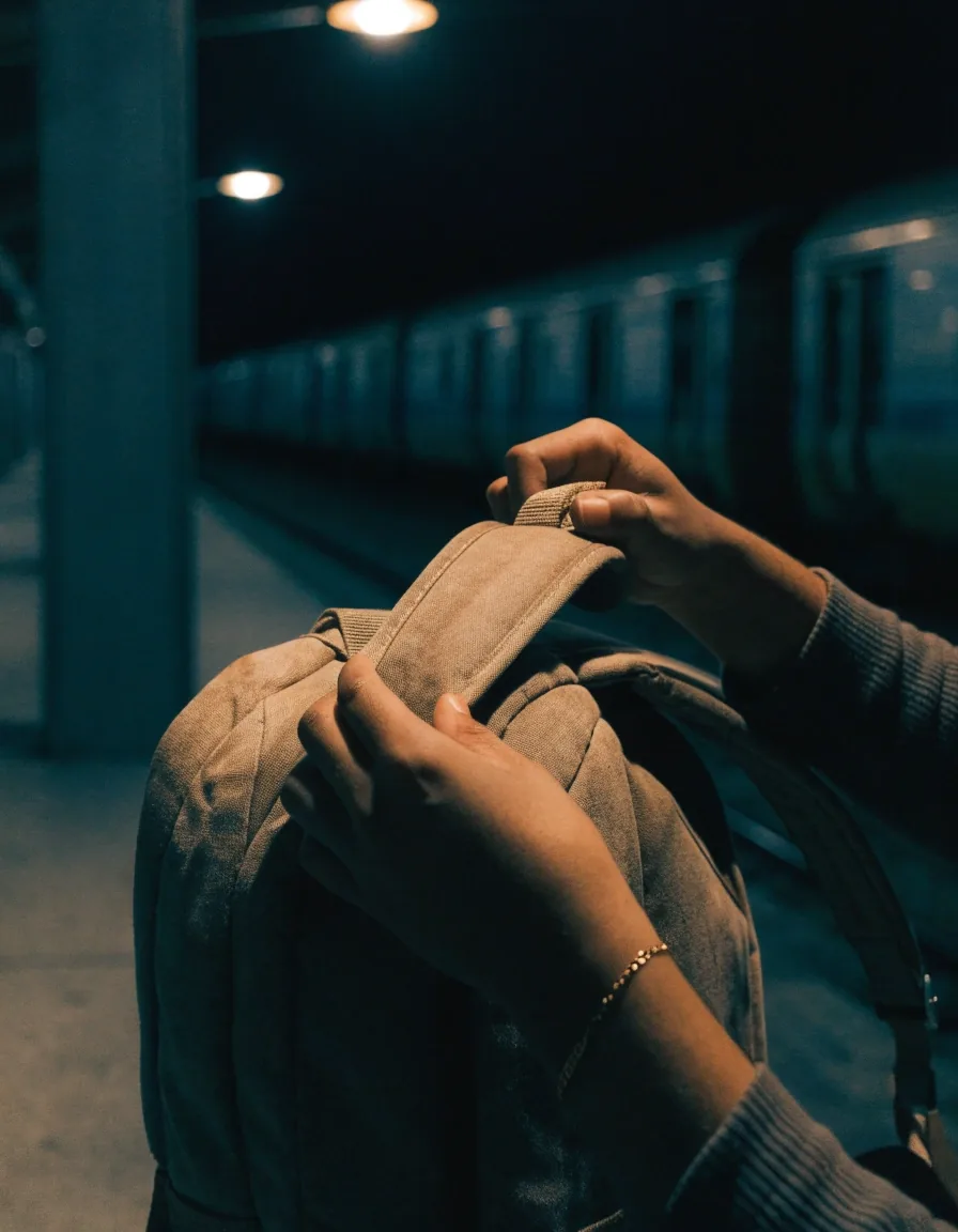 A canvas backpack leaning against a concrete bench under one streetlamp at night