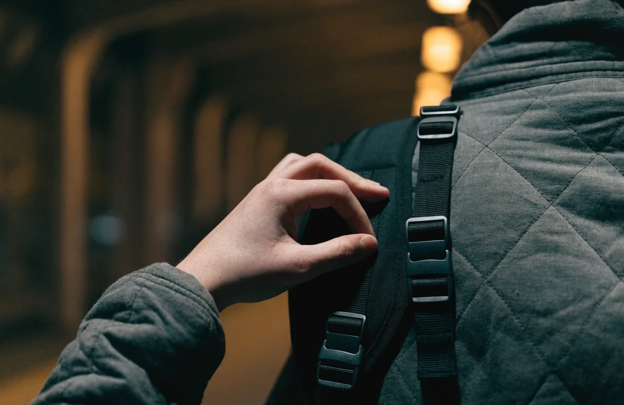 Macro view of a padded backpack shoulder strap on a concrete ledge under raking light
