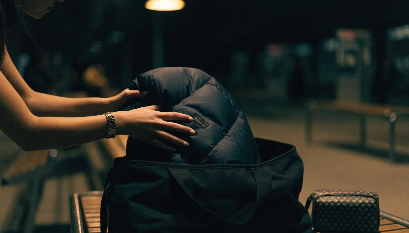 A soft weekender bag resting on wet stone steps at night under a single hard light